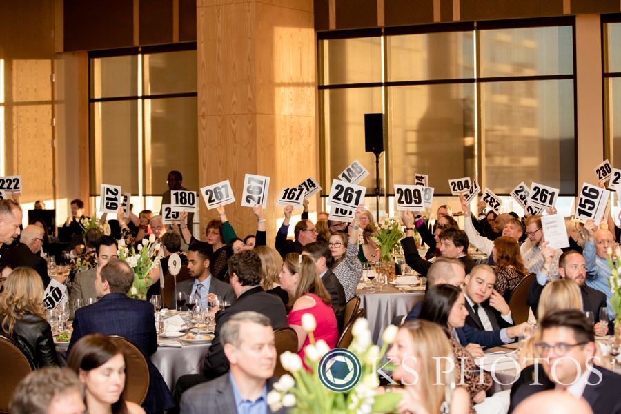 A ballroom of people holding up bid cards
