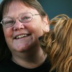 a woman smiles at the camera while holding her dog